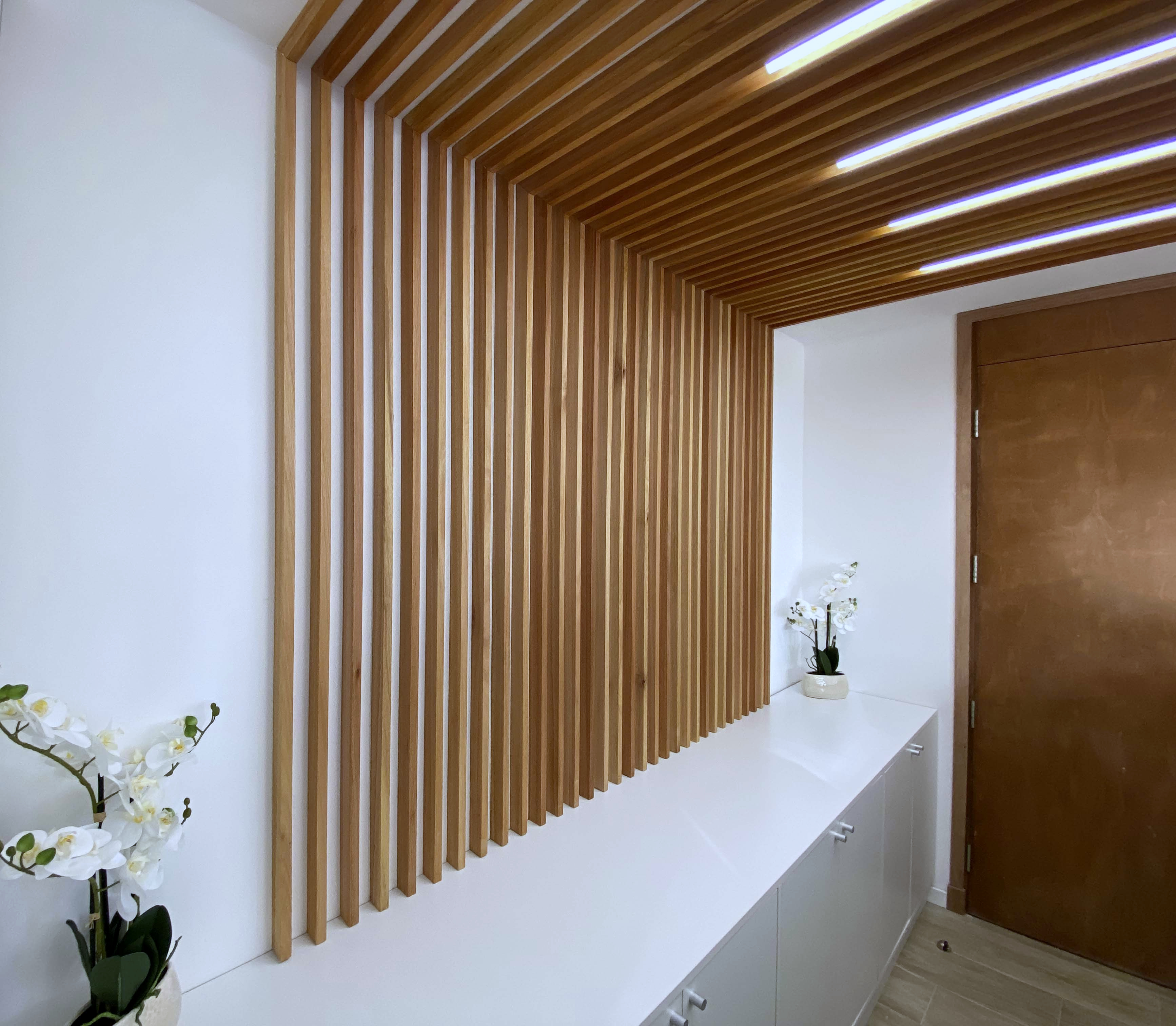 Recepción interior revestida con listones de madera e iluminación integrada