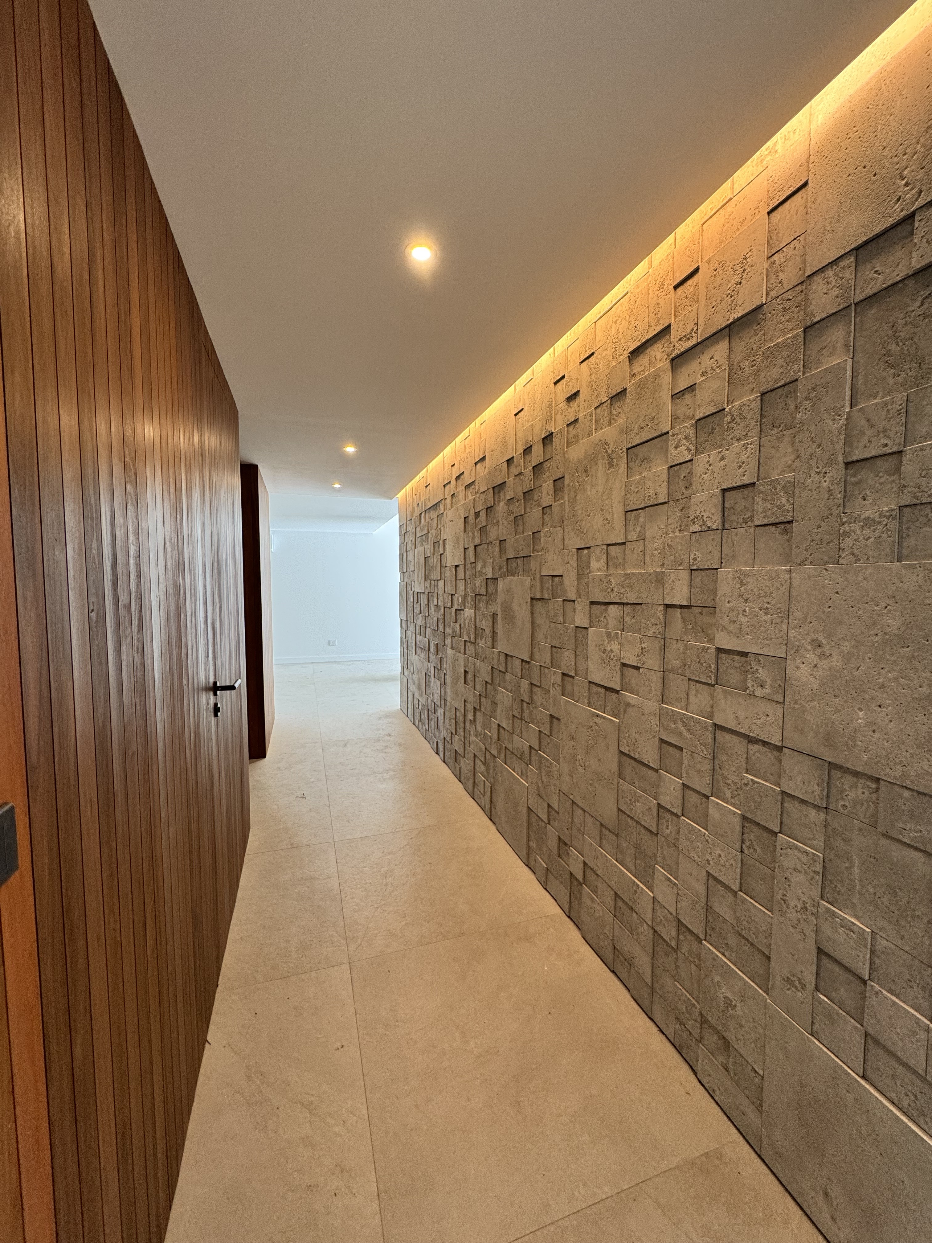 Pasillo interior con revestimientos de madera y piedra en Loma Verde