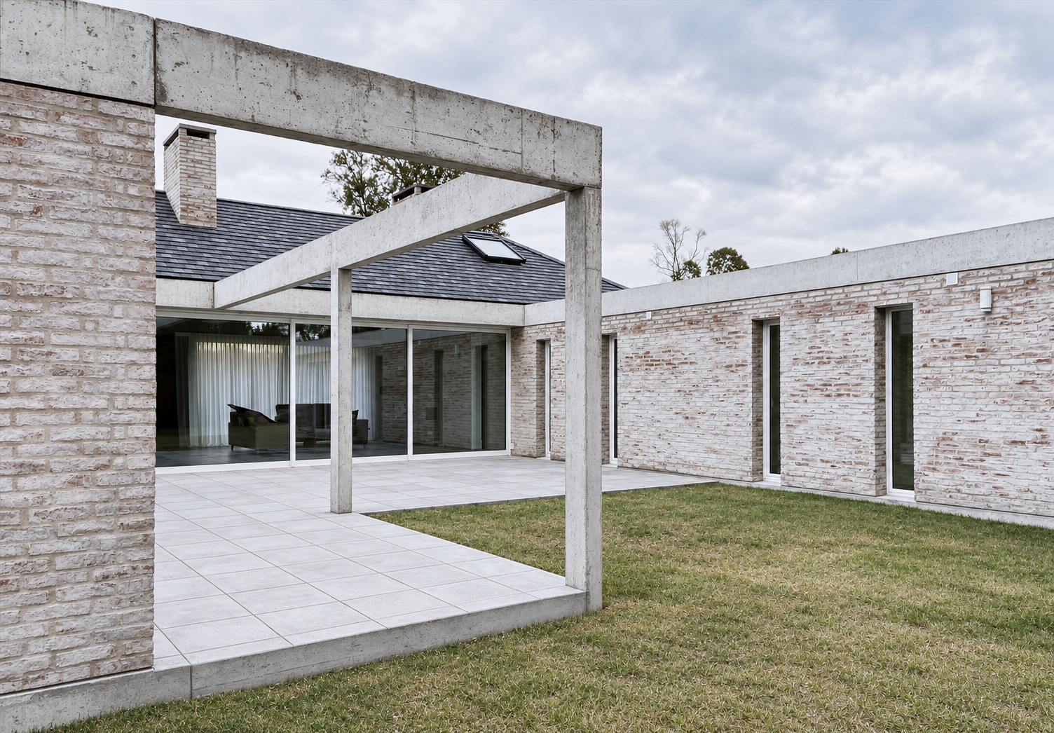Patio interior enmarcado por vigas de hormigón y muros de ladrillo claro